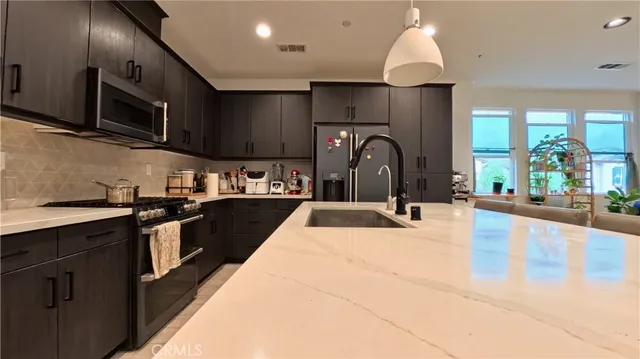 a kitchen with stainless steel appliances kitchen island granite countertop a stove a sink and a microwave