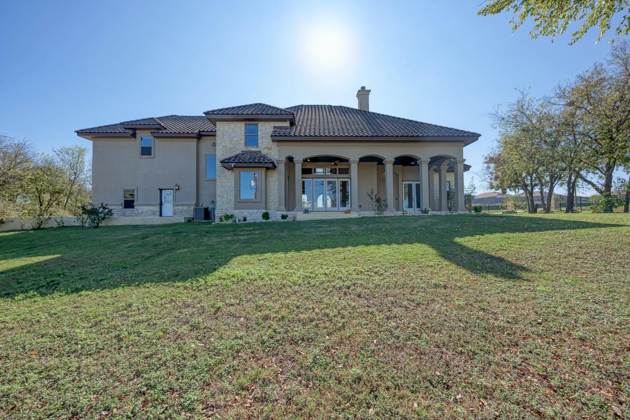 104 Spring Valley Street Hutto, TX 78634 - Photo 34 of 40 Back of house featuring a chimney, a lawn, stucco siding, covered porch, and french doors