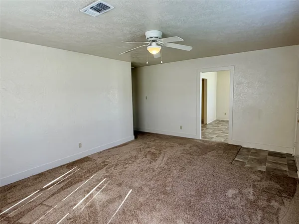 a view of an empty room with a chandelier fan