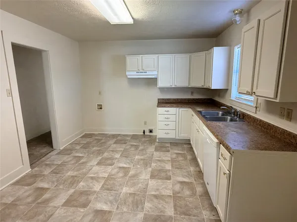 a kitchen with granite countertop a sink a stove and cabinets