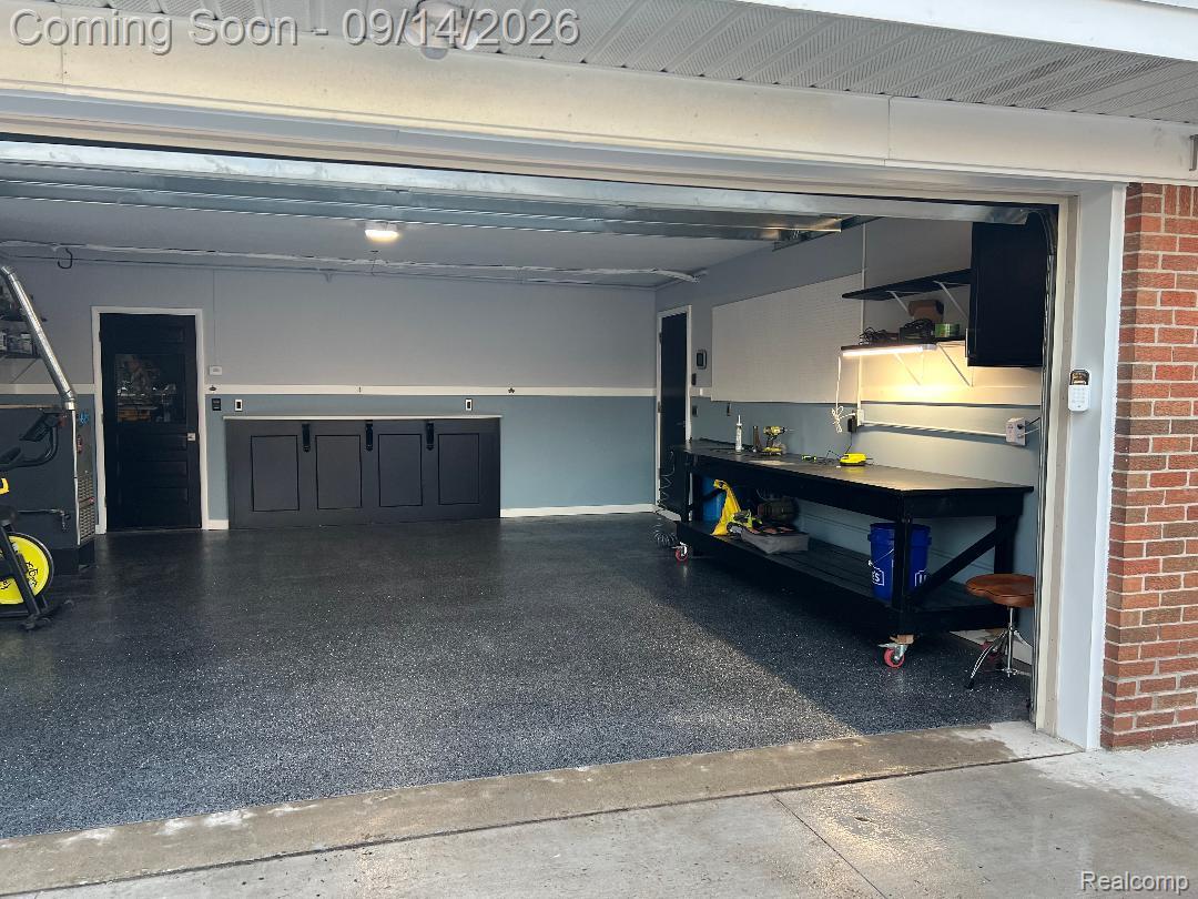 1615 Ladd Road Walled Lake, MI 48390 - Photo 21 of 28 Coated garage flooring, built-in lower cabinetry, a built-in workbench, and wall-mounted shelving