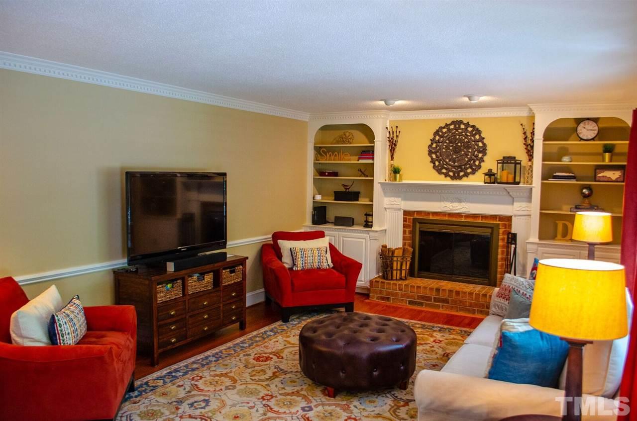 10016 Bushveld Lane Raleigh, NC 27613 - Photo 14 of 24 a living room with furniture a flat screen tv and a fireplace