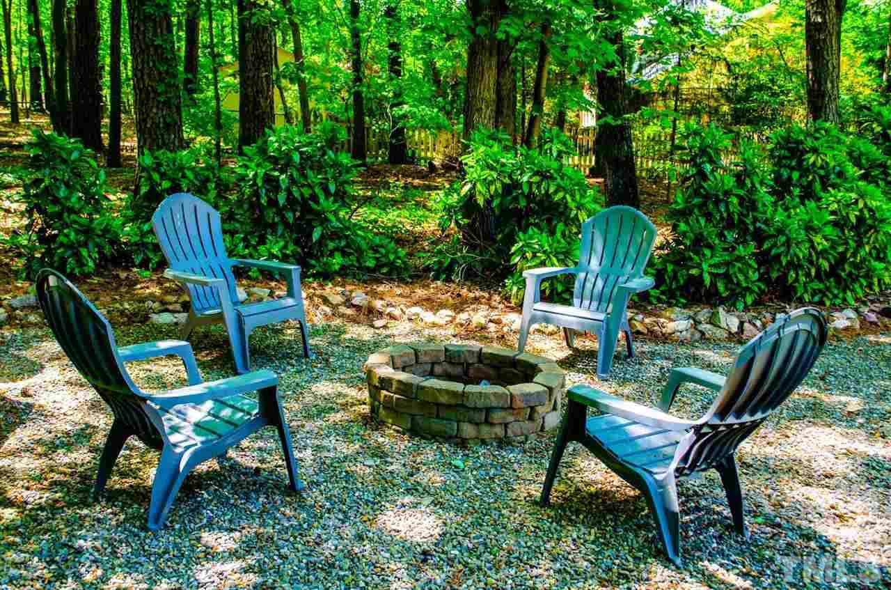 10016 Bushveld Lane Raleigh, NC 27613 - Photo 5 of 24 a backyard with table and chairs with potted plants and large trees