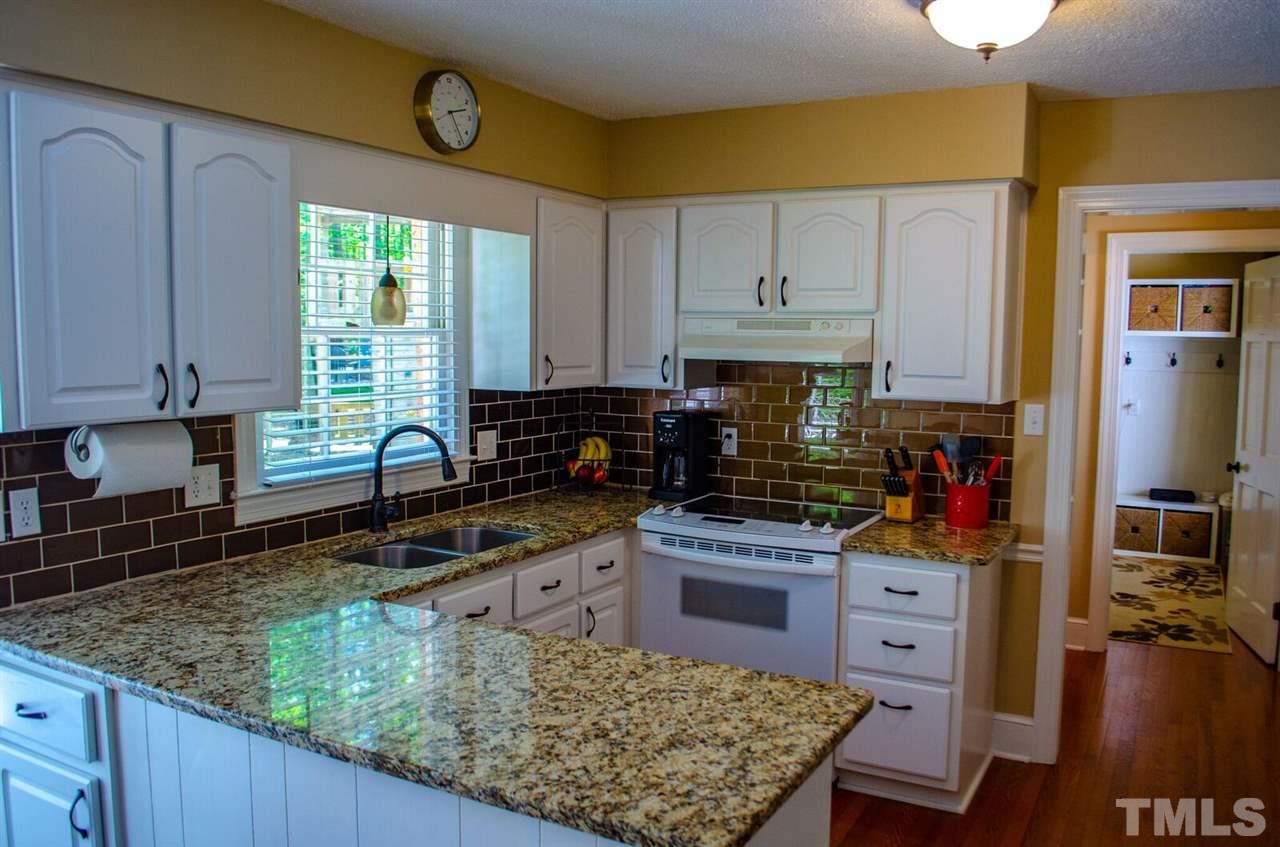 10016 Bushveld Lane Raleigh, NC 27613 - Photo 8 of 24 a kitchen with stainless steel appliances granite countertop a stove a sink dishwasher and cabinets with wooden floor