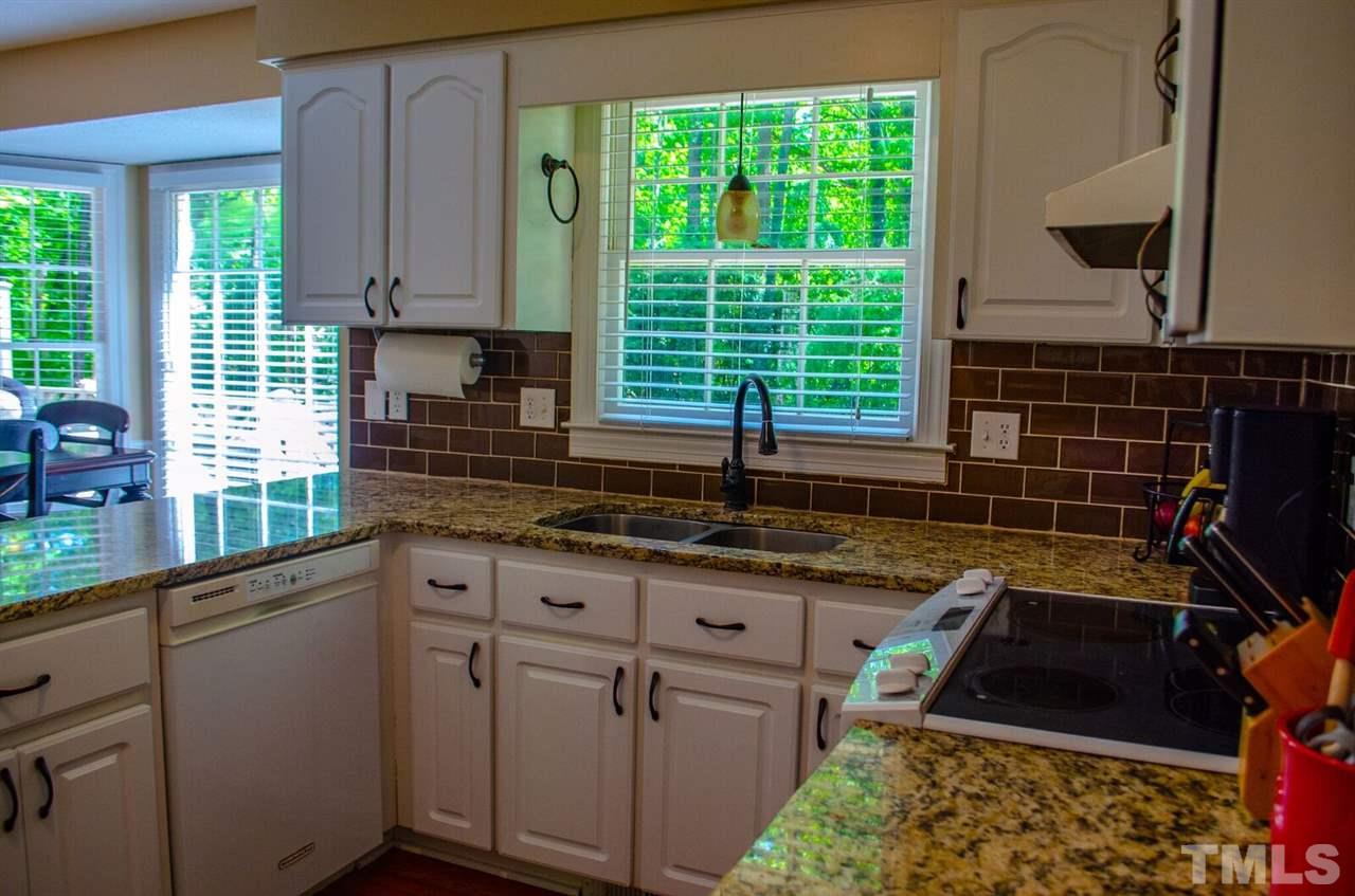 10016 Bushveld Lane Raleigh, NC 27613 - Photo 10 of 24 a kitchen with granite countertop a sink a stove and a wooden cabinets