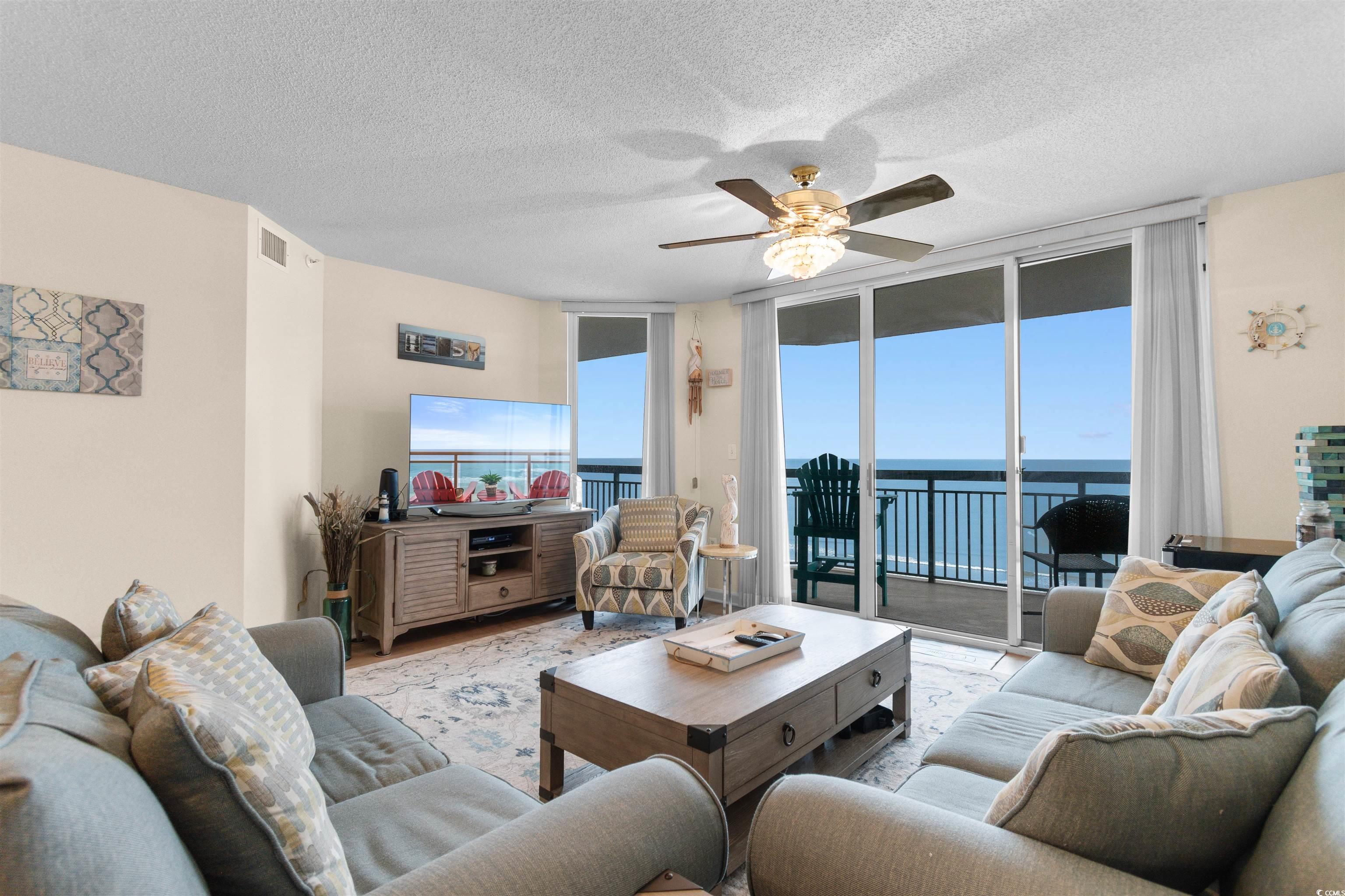 1003 South Ocean Boulevard, Unit 902 North Myrtle Beach, SC 29582 - Photo 12 of 40 Living room featuring a wall of windows, a textured ceiling, ceiling fan, and wood finished floors