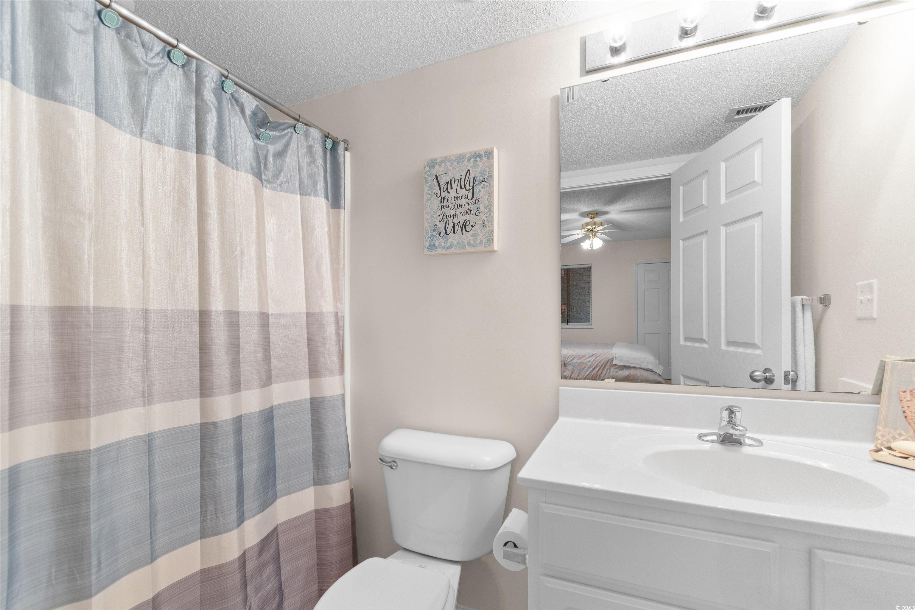 1003 South Ocean Boulevard, Unit 902 North Myrtle Beach, SC 29582 - Photo 23 of 40 Ensuite bathroom featuring a shower with shower curtain, vanity, a textured ceiling, and a ceiling fan