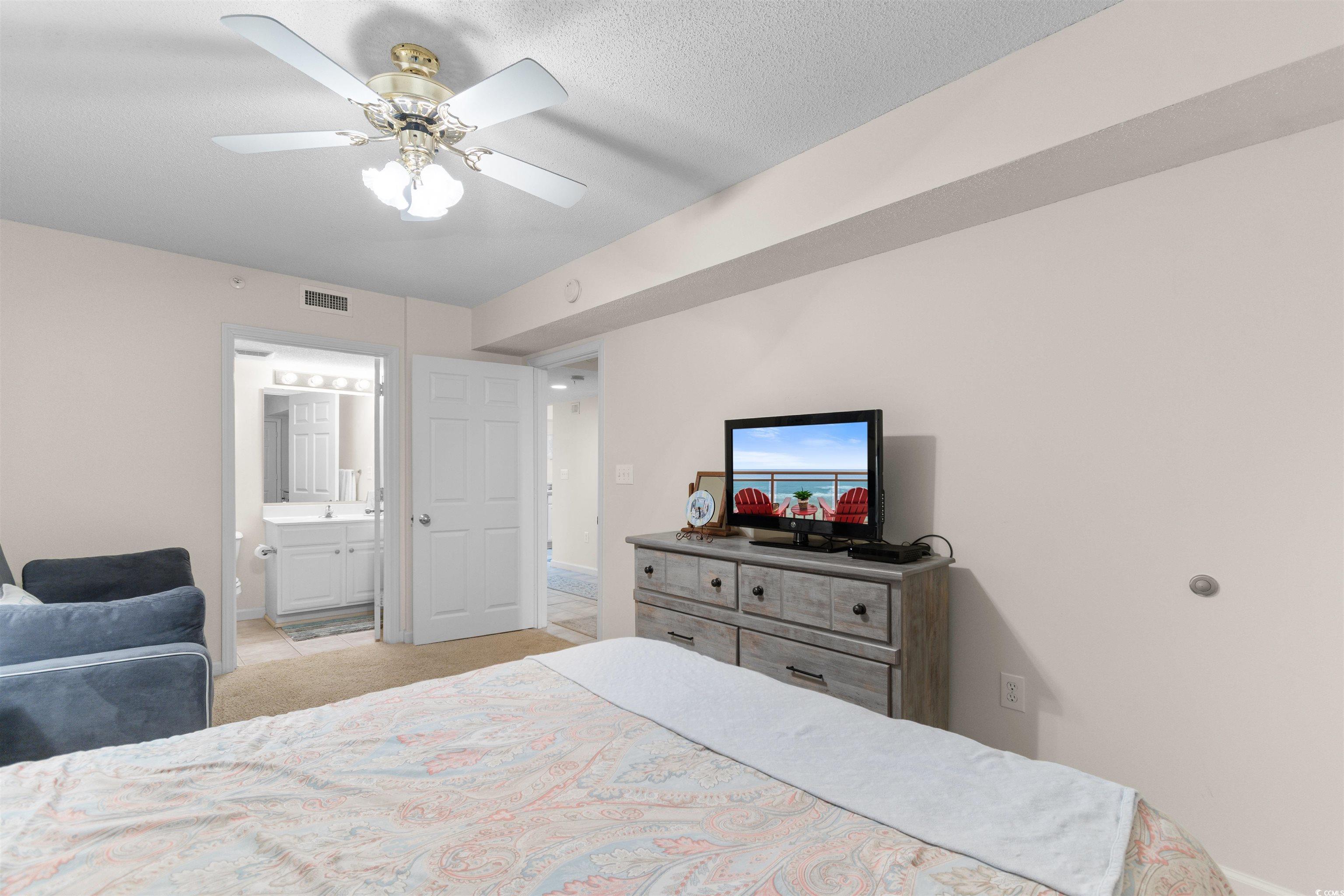 1003 South Ocean Boulevard, Unit 902 North Myrtle Beach, SC 29582 - Photo 25 of 40 Bedroom with ceiling fan, light carpet, ensuite bathroom, and a textured ceiling