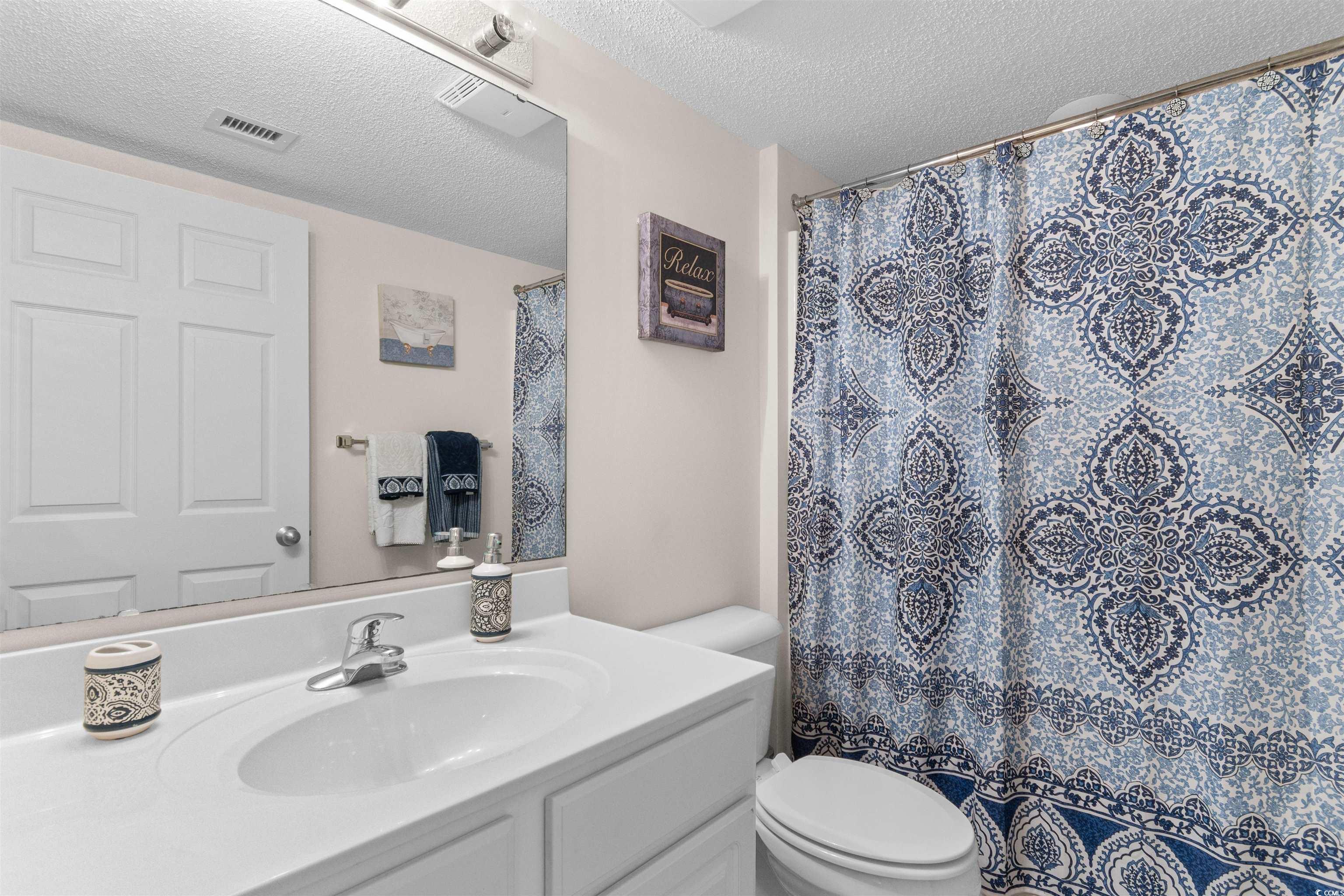 1003 South Ocean Boulevard, Unit 902 North Myrtle Beach, SC 29582 - Photo 28 of 40 Full bathroom featuring a textured ceiling, vanity, and a shower with curtain
