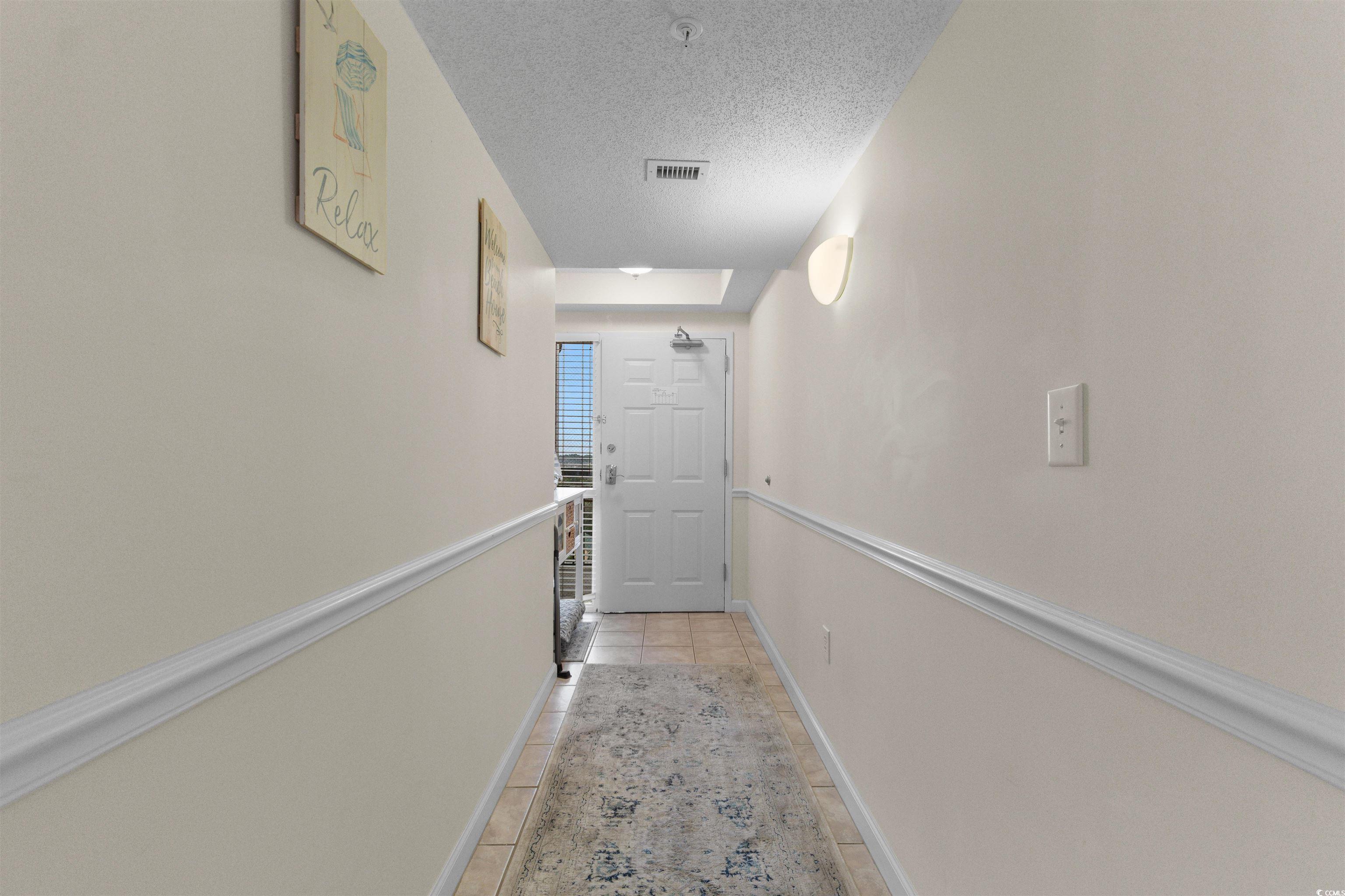 1003 South Ocean Boulevard, Unit 902 North Myrtle Beach, SC 29582 - Photo 5 of 40 Corridor featuring a textured ceiling and light tile patterned floors