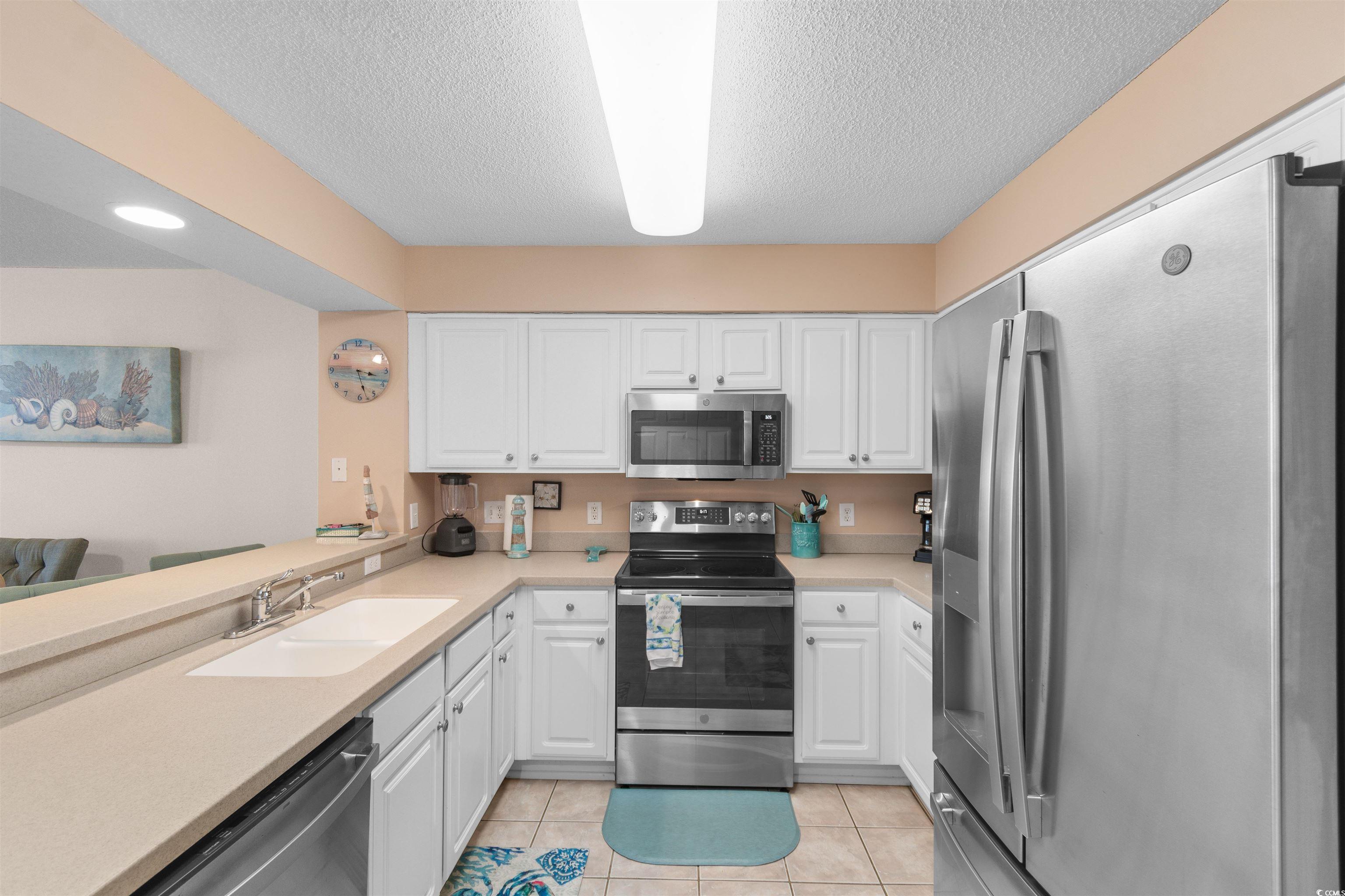 1003 South Ocean Boulevard, Unit 902 North Myrtle Beach, SC 29582 - Photo 6 of 40 Kitchen featuring appliances with stainless steel finishes, white cabinetry, light tile patterned floors, and a textured ceiling