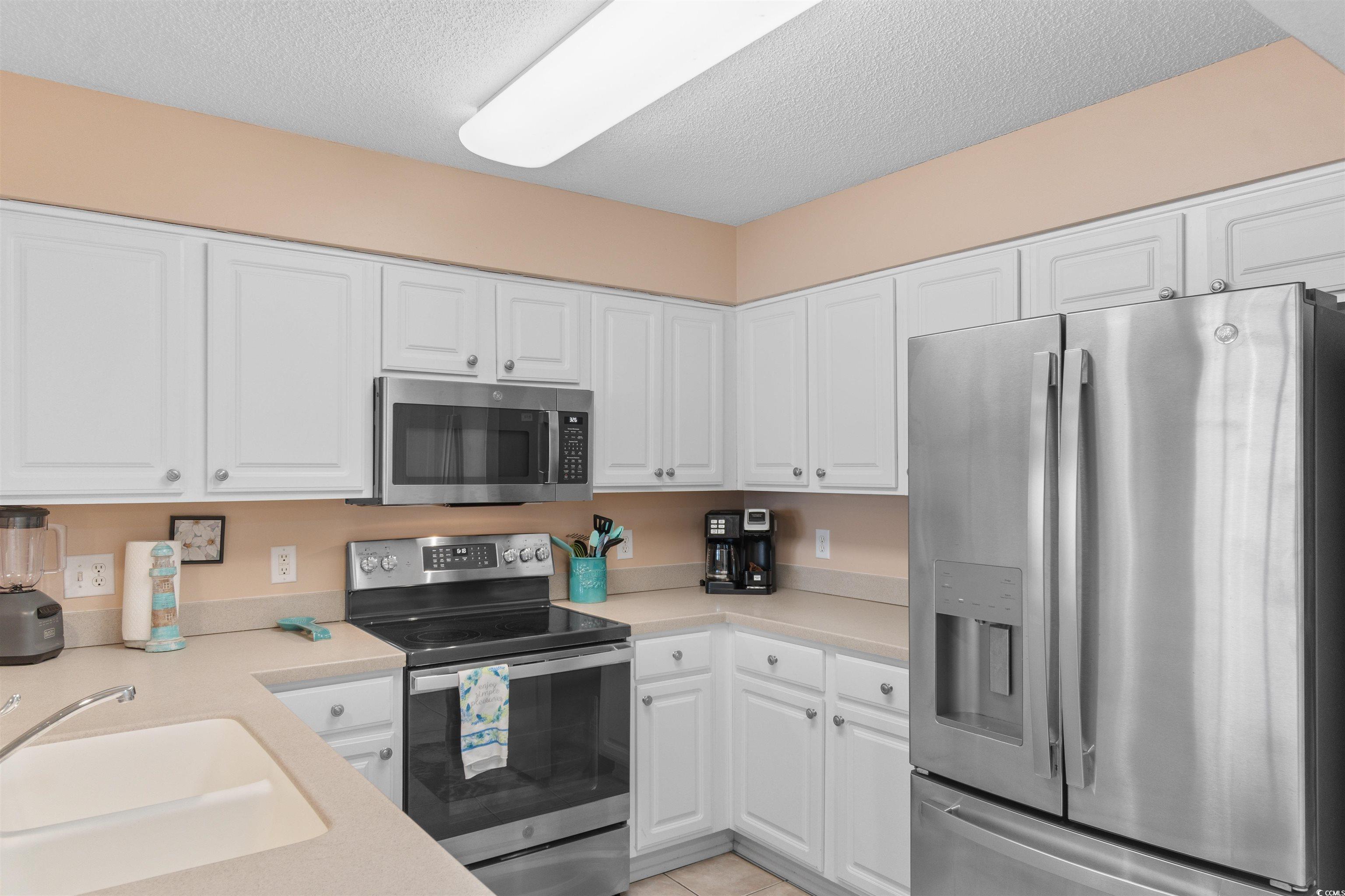 1003 South Ocean Boulevard, Unit 902 North Myrtle Beach, SC 29582 - Photo 7 of 40 Kitchen with appliances with stainless steel finishes, a textured ceiling, white cabinets, and light countertops