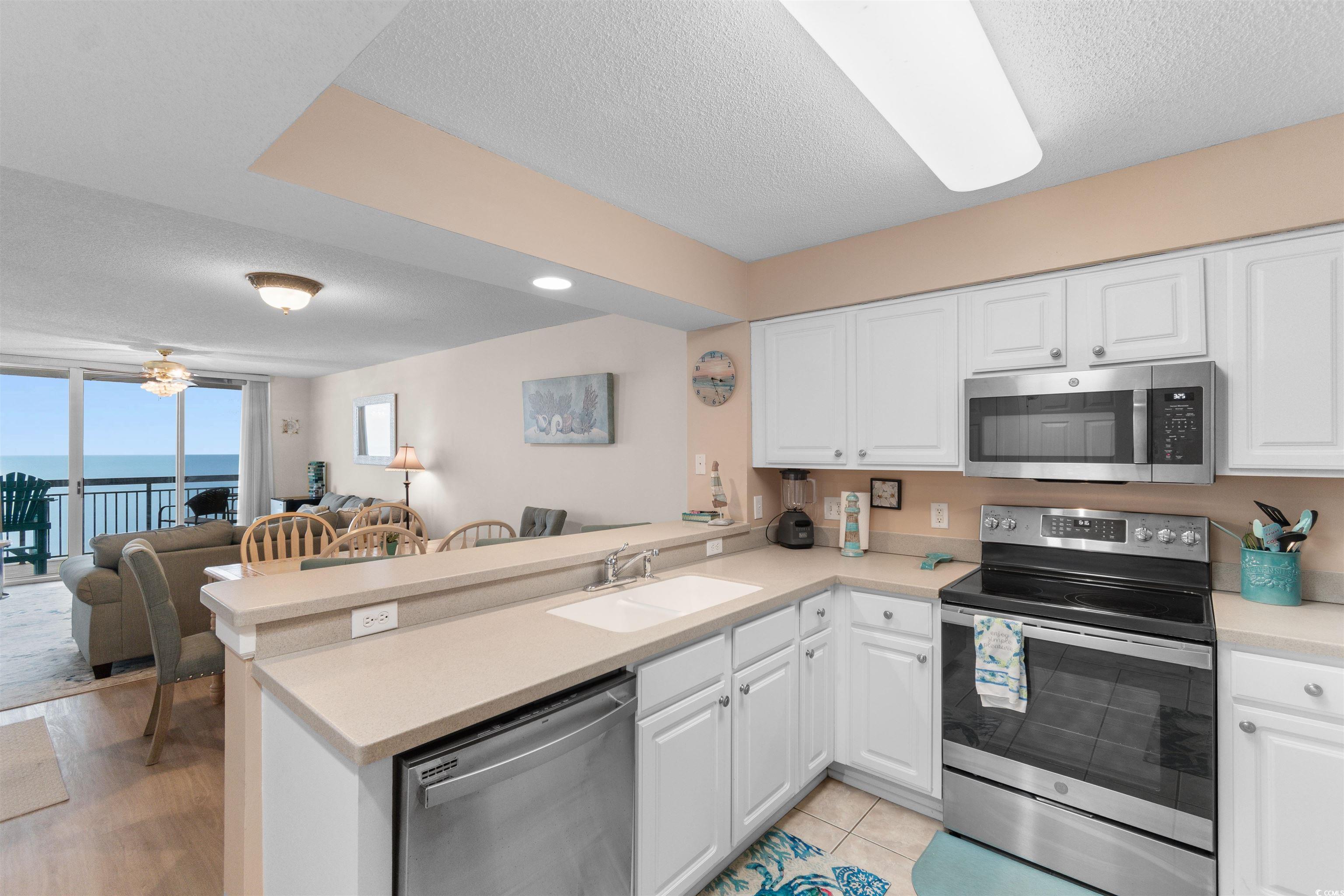 1003 South Ocean Boulevard, Unit 902 North Myrtle Beach, SC 29582 - Photo 40 of 40 Kitchen with open floor plan, stainless steel appliances, a textured ceiling, a peninsula, and white cabinets