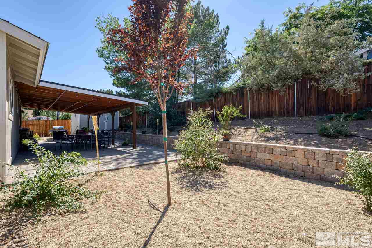 12085 Kernite Street Reno, NV 89506 - Photo 24 of 29 a view of patio with table and chairs under an umbrella with large trees