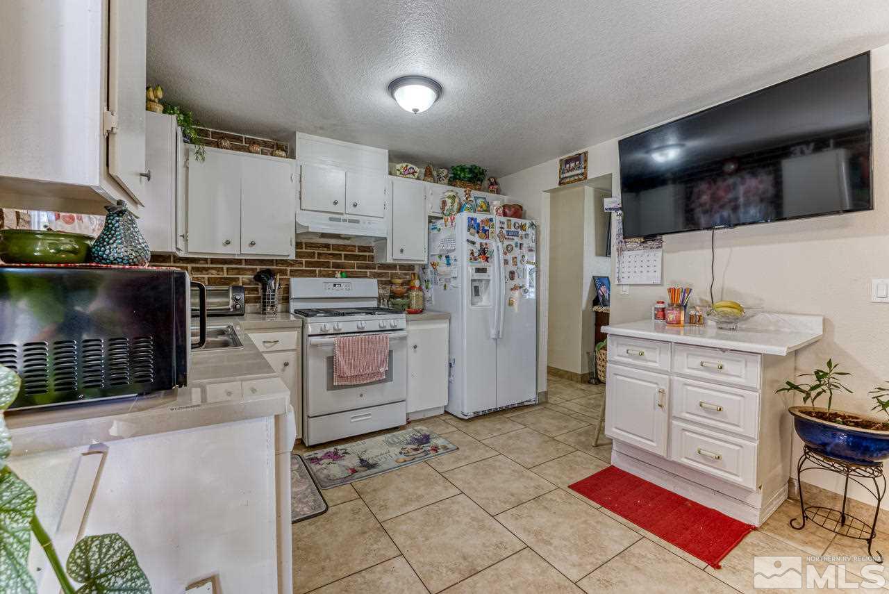 12085 Kernite Street Reno, NV 89506 - Photo 10 of 29 a kitchen with stainless steel appliances a stove a sink a chimney a refrigerator and cabinets