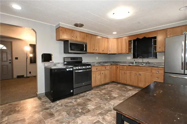 a kitchen with stainless steel appliances granite countertop a stove a sink and a refrigerator