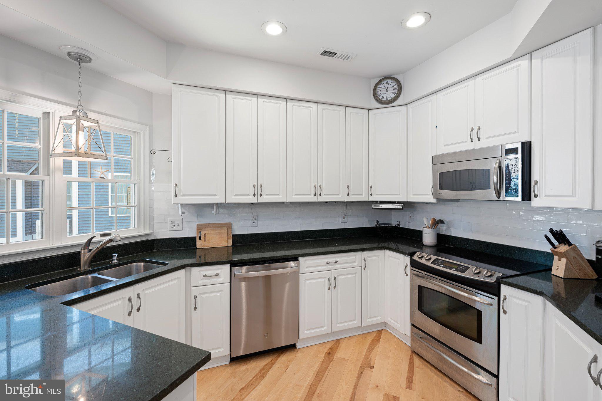 718 Foxtail Drive Bethany Beach, DE 19930 - Photo 12 of 39 a kitchen with granite countertop white cabinets and black appliances