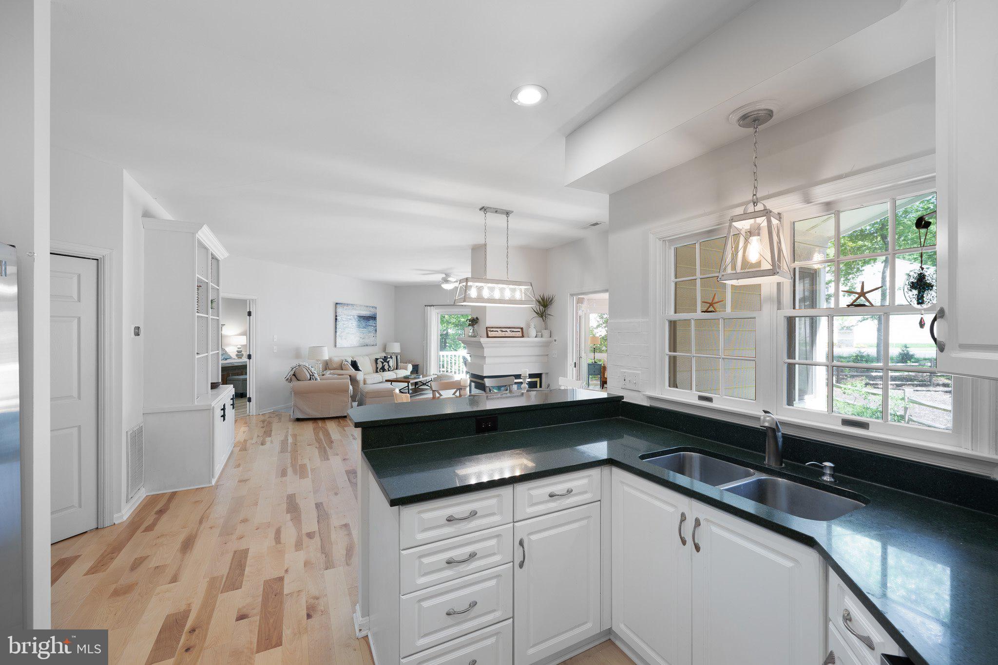 718 Foxtail Drive Bethany Beach, DE 19930 - Photo 14 of 39 a large kitchen with granite countertop a sink dishwasher a stove and white cabinets with wooden floor