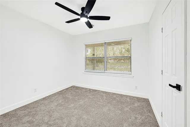 an empty room with a window and a ceiling fan
