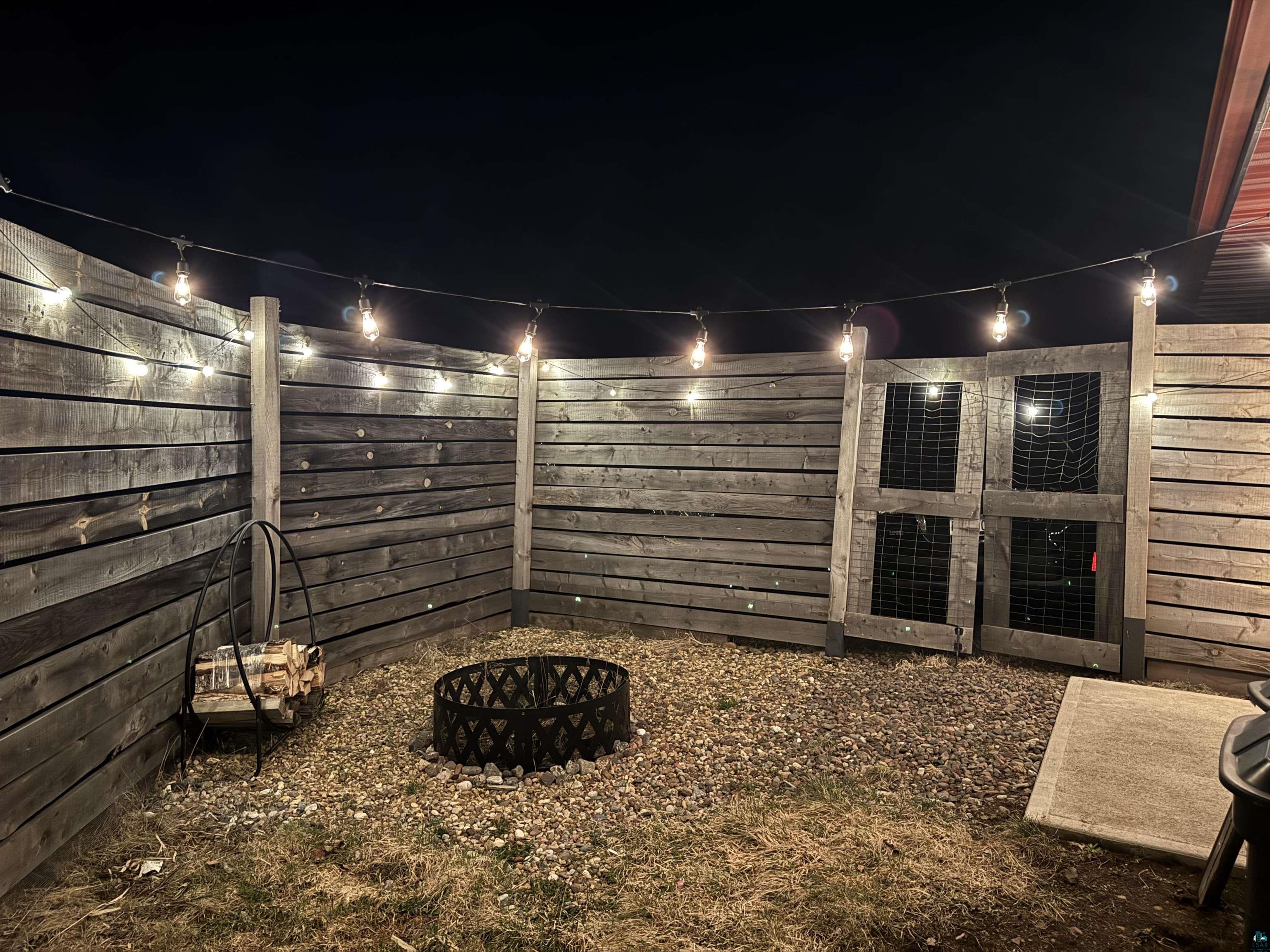 265 Mink Ranch Road Lutsen, MN 55612 - Photo 11 of 36 Private outdoor space featuring a wood fence, gravel patio, and string lighting