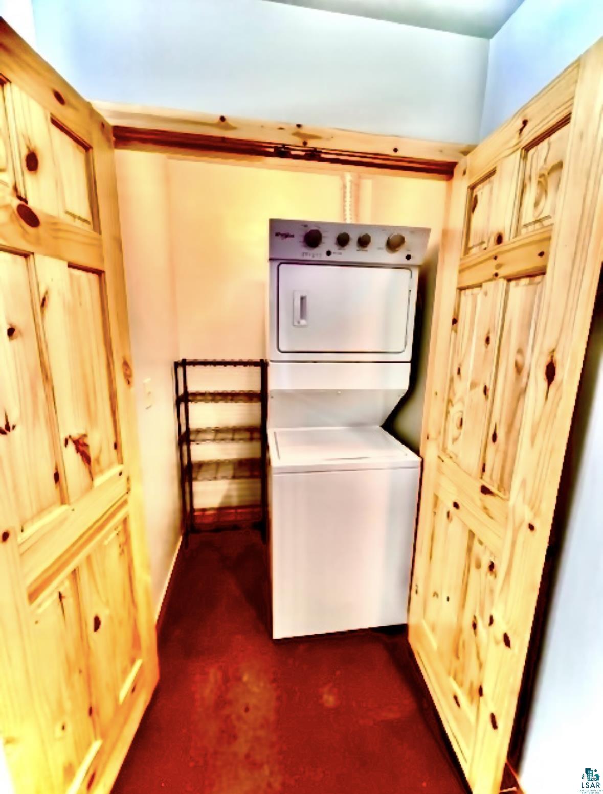 265 Mink Ranch Road Lutsen, MN 55612 - Photo 19 of 25 Laundry area with dark carpet and stacked washer and clothes dryer