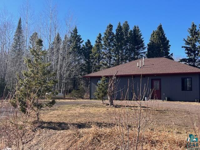 265 Mink Ranch Road Lutsen, MN 55612 - Photo 2 of 36 Single-story home featuring dark gray siding, a reddish-brown shingle roof, and a red entry door