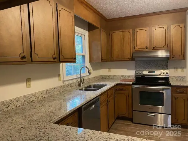 a kitchen with stainless steel appliances granite countertop a sink and cabinets with wooden floor