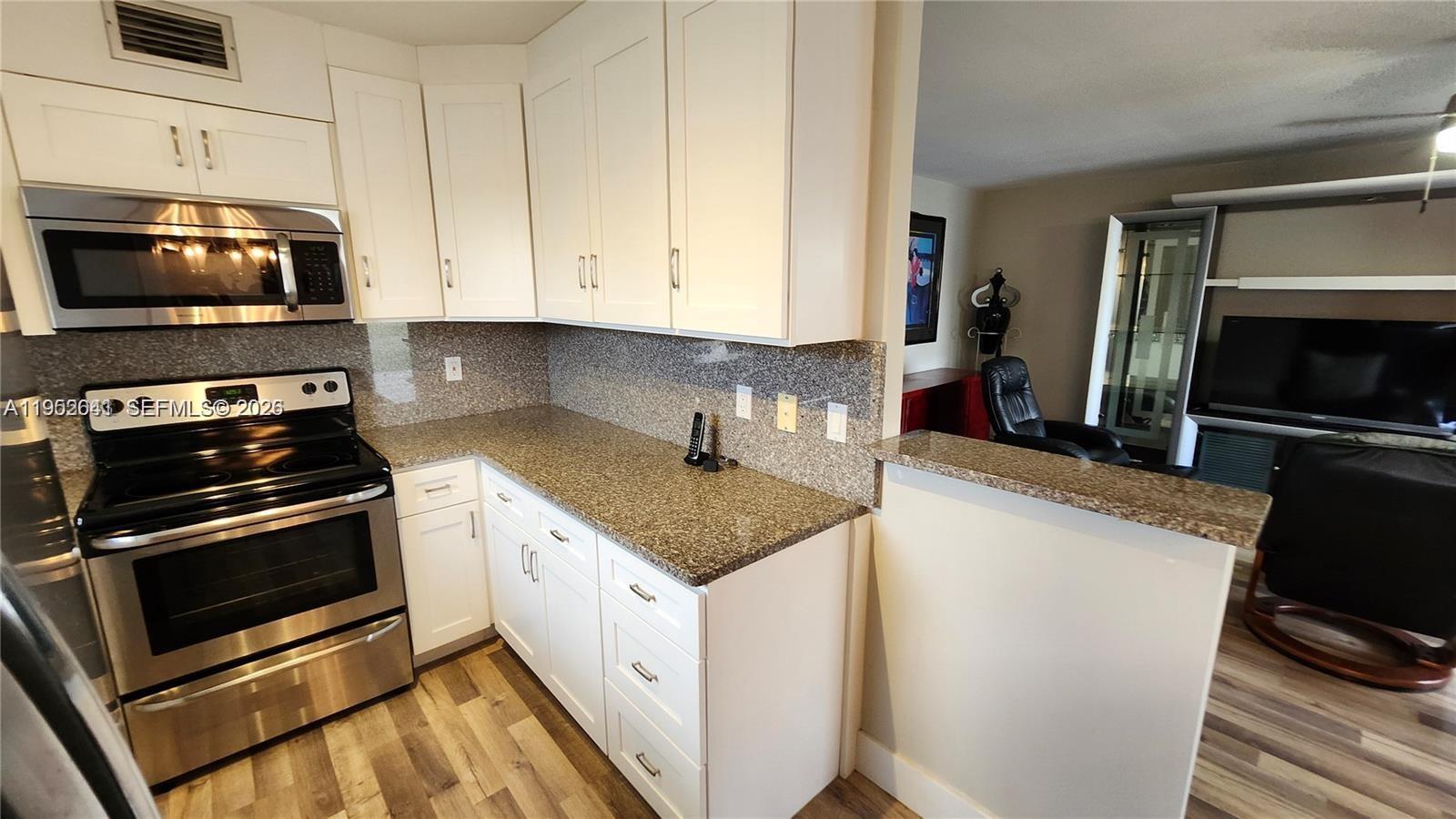 756 Flanders P Delray Beach, Unit 756 Delray Beach, FL 33484 - Photo 2 of 46 a kitchen with granite countertop a sink stove and microwave