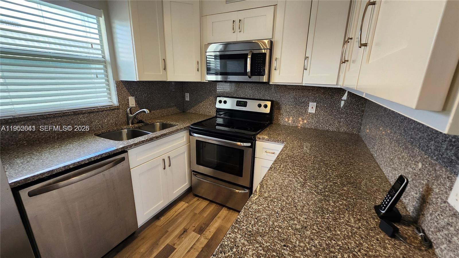 756 Flanders P Delray Beach, Unit 756 Delray Beach, FL 33484 - Photo 3 of 46 a kitchen with granite countertop a sink a stove and microwave