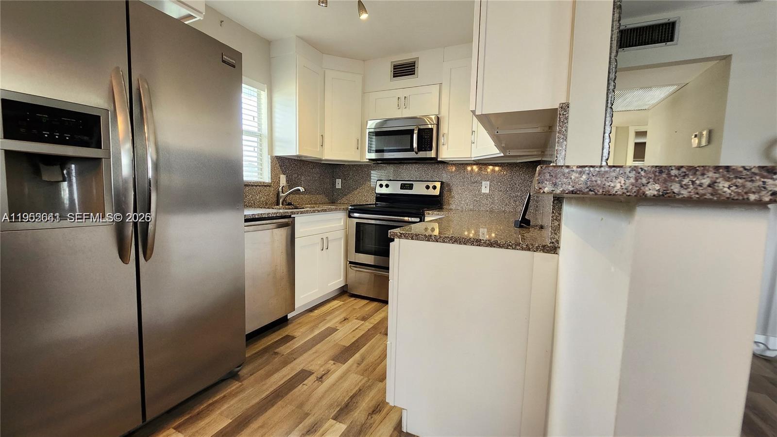 756 Flanders P Delray Beach, Unit 756 Delray Beach, FL 33484 - Photo 4 of 46 a kitchen with stainless steel appliances granite countertop a refrigerator a stove and a sink with wooden floor