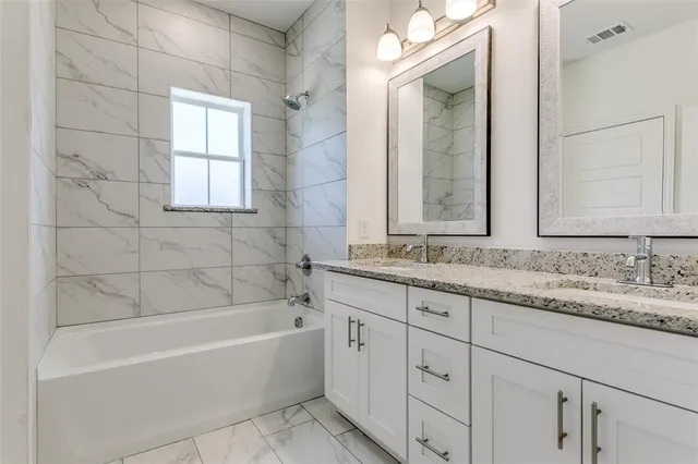 a bathroom with a granite countertop bathtub a sink and a window