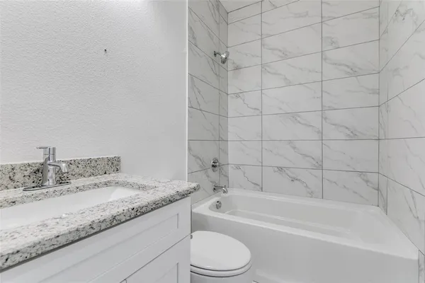 a bathroom with a granite countertop bathtub toilet sink and mirror