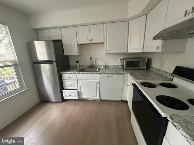 a kitchen with stainless steel appliances a sink a stove a refrigerator and cabinets