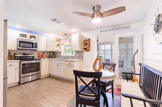 a kitchen with stainless steel appliances kitchen island granite countertop a dining table chairs and a refrigerator