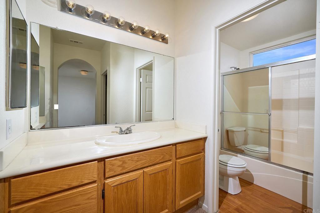 297 Diamante Way Oceanside, CA 92056 - Photo 14 of 28 a bathroom with a granite countertop sink toilet a mirror and shower