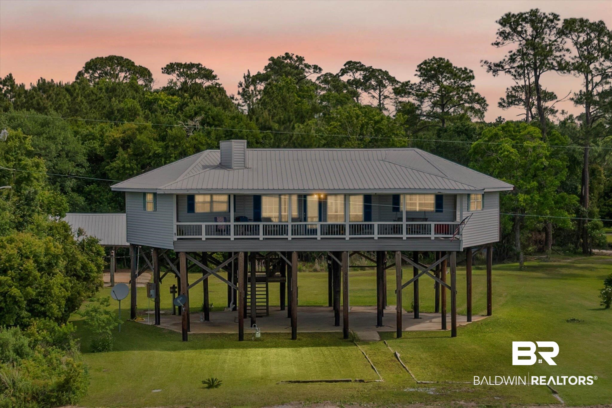 9100 Shell Belt Road Coden, AL 36523 - Photo 2 of 38 Elevated coastal-style residence featuring a metal roof, a full-width covered porch with white railings, and a ground-level covered parking area