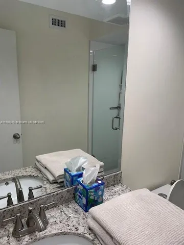 a bathroom with a granite countertop sink a toilet a mirror and shower