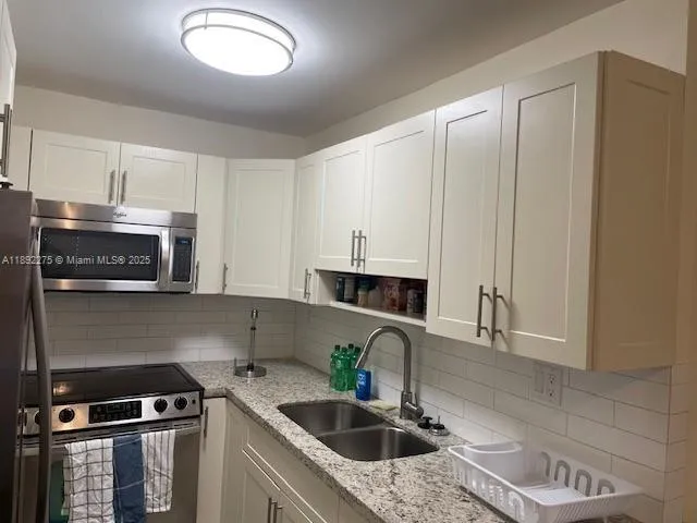 a kitchen with stainless steel appliances granite countertop a sink a stove and a microwave