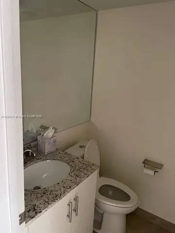 a bathroom with a granite countertop sink a toilet and a mirror
