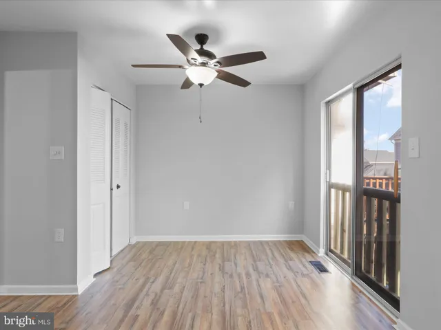 a view of empty room with wooden floor and fan