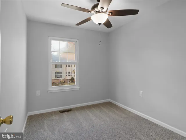 an empty room with a window and a fan