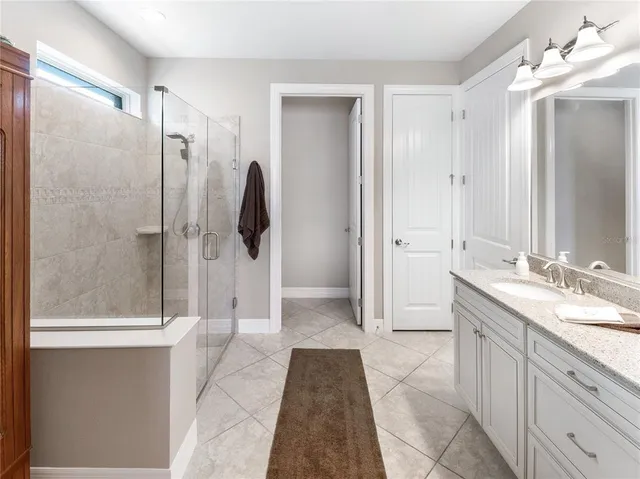 a spacious bedroom with a bed a couch and potted plant in it