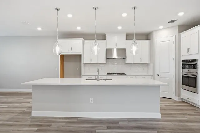 a large kitchen with kitchen island a sink stainless steel appliances and cabinets