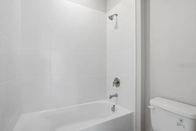 a white bath tub sitting next to a white toilet and a shower