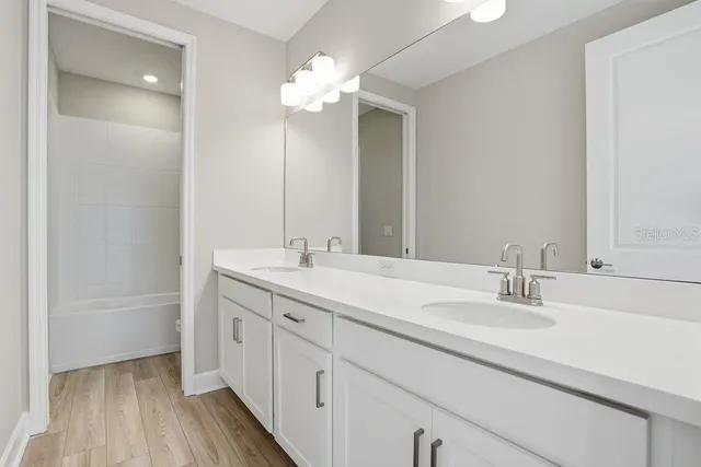 a bathroom with a double vanity sink mirror and cabinets
