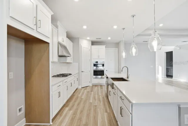 a large kitchen with stainless steel appliances lots of counter space and wooden floor
