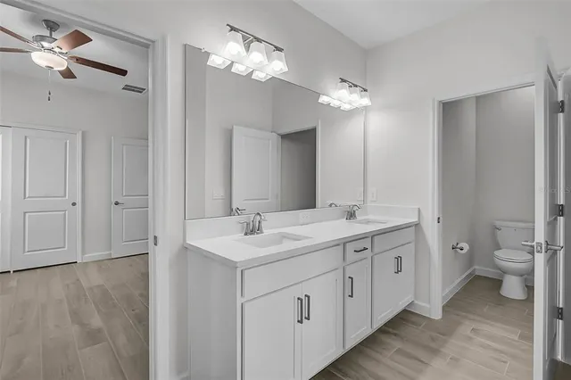 a spacious bathroom with a double vanity sink a toilet and a mirror