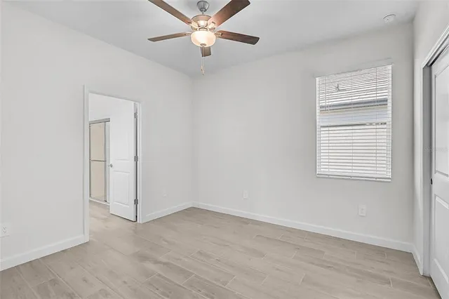 an empty room with a window and a fan