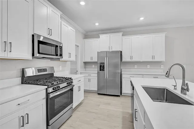 a kitchen with refrigerator a microwave a sink and cabinets