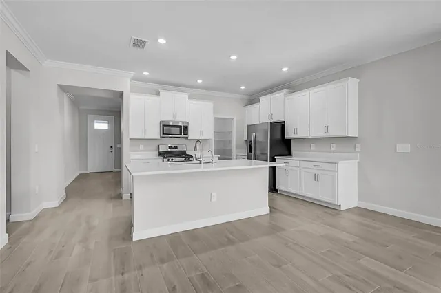 a large white kitchen with kitchen island a sink a center island stainless steel appliances and a cabinets